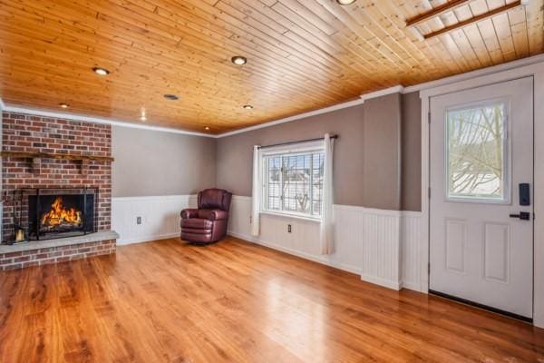 foyer with wood-type flooring, a brick fireplace, crown molding, and wooden ceiling