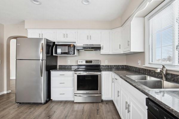 kitchen with sink, white cabinetry, dark stone counters, and black appliances