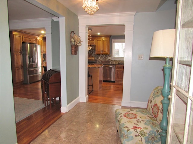 corridor featuring light tile patterned floors, crown molding, and an inviting chandelier