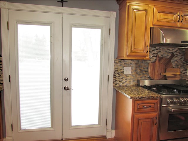 kitchen featuring extractor fan, tasteful backsplash, french doors, dark stone counters, and high end stainless steel range