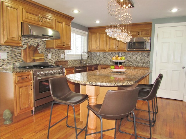 kitchen featuring an inviting chandelier, appliances with stainless steel finishes, stone countertops, and a kitchen island