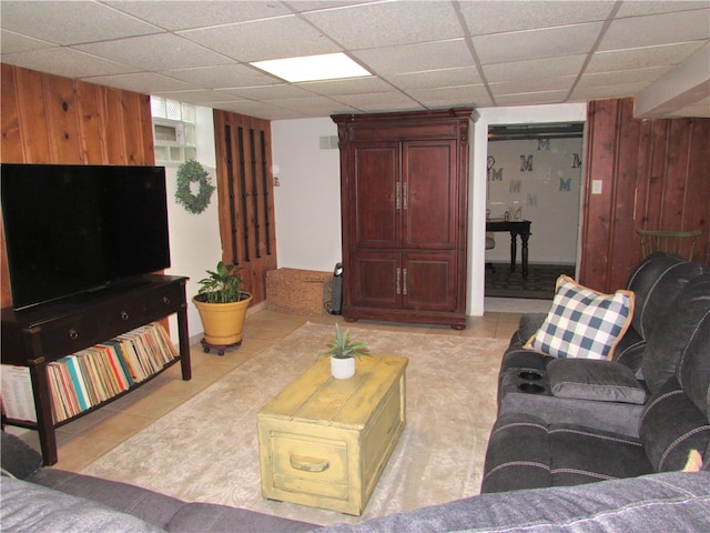 living room with a paneled ceiling, wood walls, and light tile patterned flooring