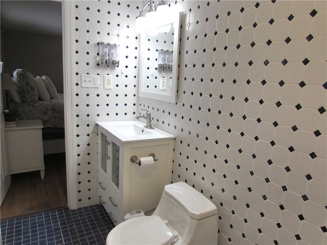 bathroom with toilet, vanity, tile walls, and tile patterned floors