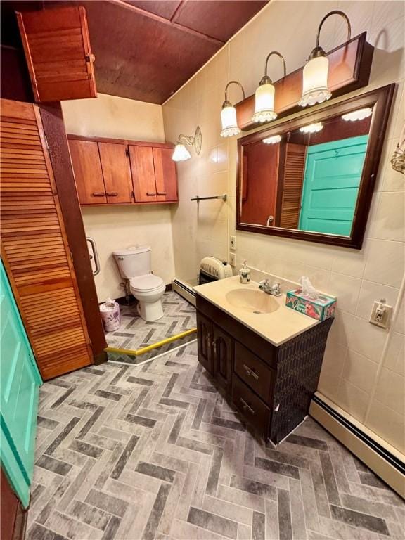 bathroom with toilet, vanity, and a baseboard heating unit