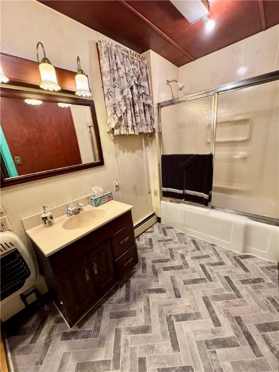 bathroom with vanity, shower / bath combination with glass door, and a baseboard heating unit