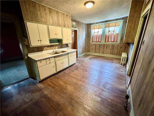 kitchen featuring a textured ceiling, wooden walls, sink, radiator heating unit, and dark hardwood / wood-style floors