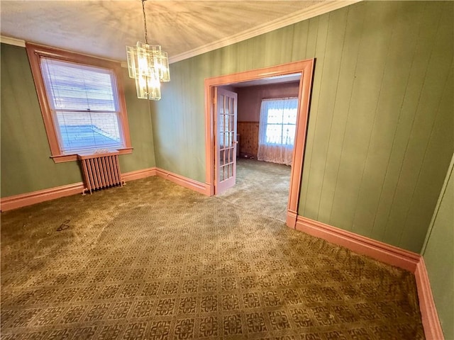 spare room featuring radiator, crown molding, carpet, and a notable chandelier