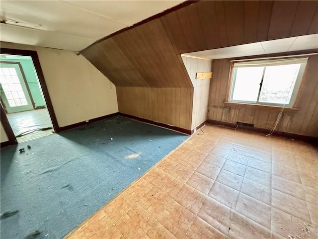 bonus room featuring lofted ceiling and wooden walls