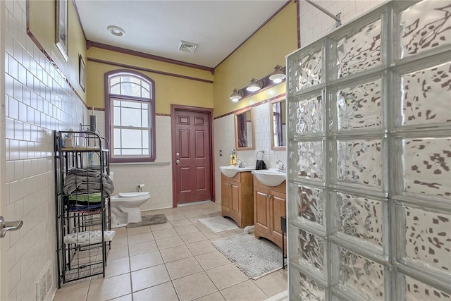 bathroom featuring tile patterned flooring, crown molding, toilet, vanity, and tile walls