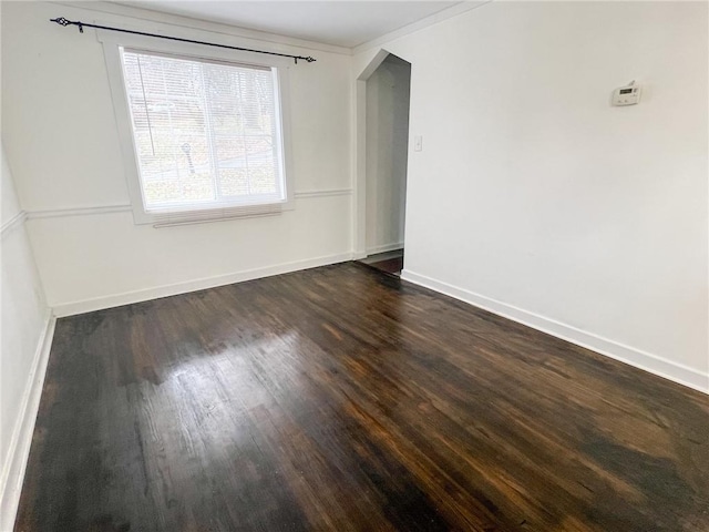 empty room with dark hardwood / wood-style floors and ornamental molding