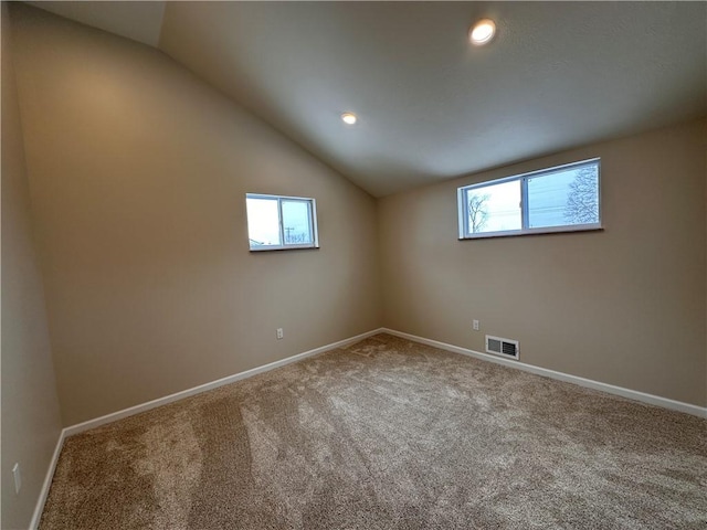 carpeted spare room featuring vaulted ceiling and a healthy amount of sunlight