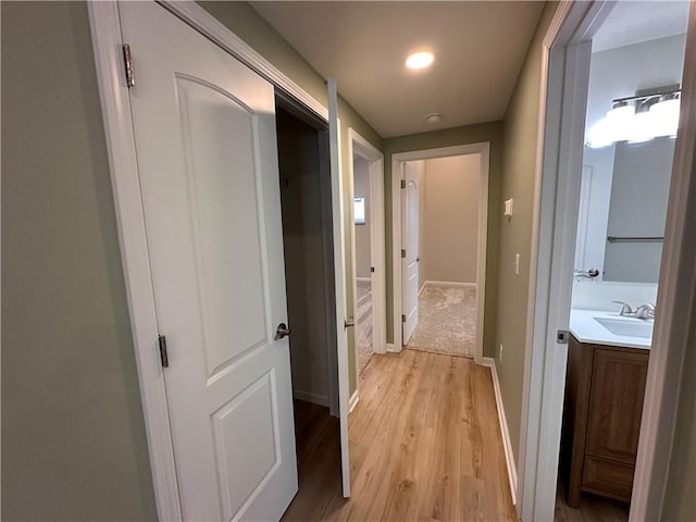 hall with light wood-type flooring and sink