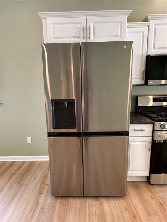 kitchen with white cabinets, appliances with stainless steel finishes, and light hardwood / wood-style floors