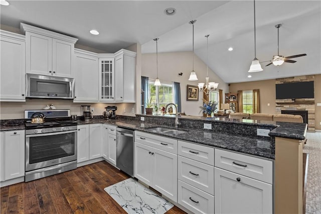 kitchen with white cabinetry, sink, stainless steel appliances, decorative light fixtures, and ceiling fan with notable chandelier