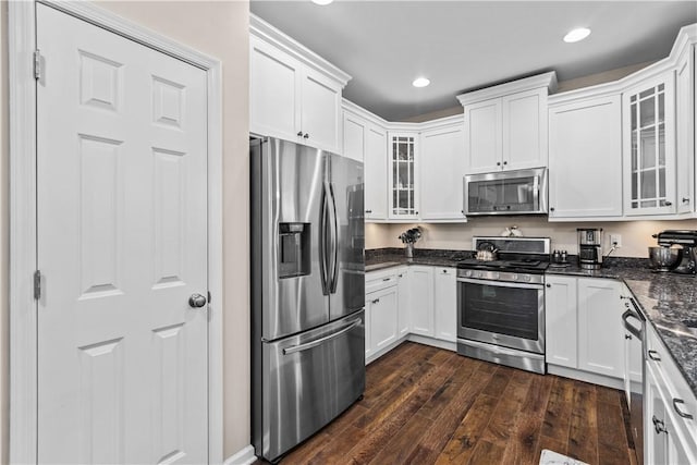 kitchen with dark hardwood / wood-style floors, dark stone countertops, white cabinetry, and stainless steel appliances