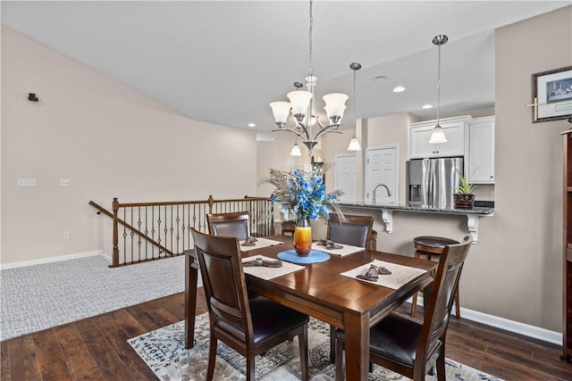 dining room with sink, dark wood-type flooring, and an inviting chandelier