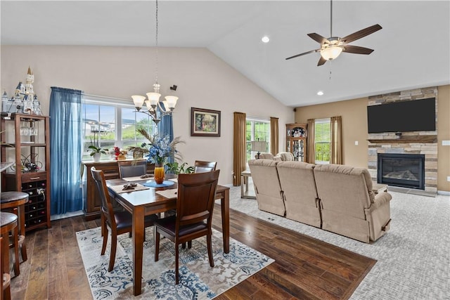 dining area with plenty of natural light, a fireplace, ceiling fan with notable chandelier, and dark wood-type flooring