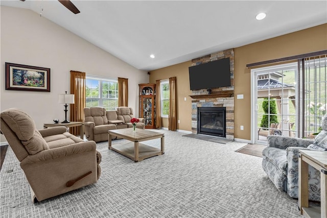 carpeted living room featuring a stone fireplace, ceiling fan, and high vaulted ceiling