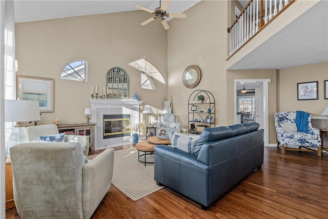 living room with a towering ceiling, ceiling fan, and dark wood-type flooring