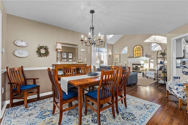 dining space with dark hardwood / wood-style floors, vaulted ceiling, and an inviting chandelier