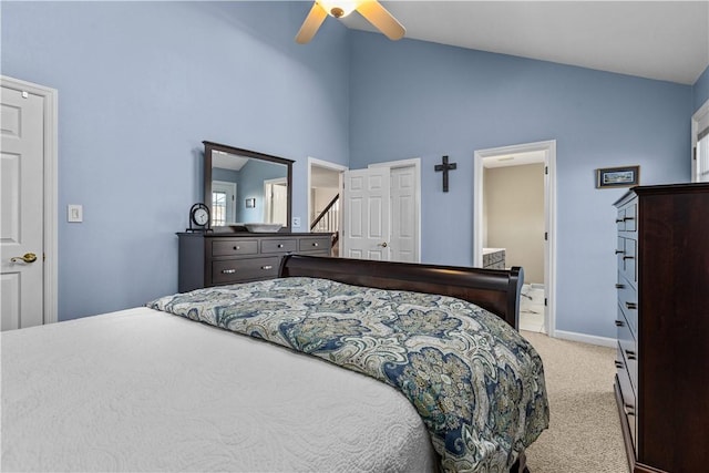 bedroom with ceiling fan, vaulted ceiling, light carpet, and ensuite bath