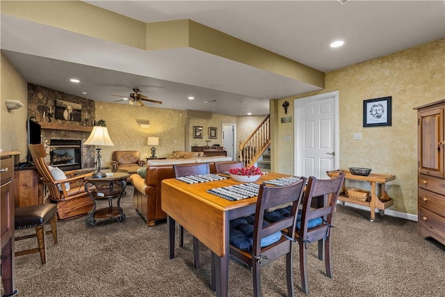 carpeted dining area featuring ceiling fan and a fireplace