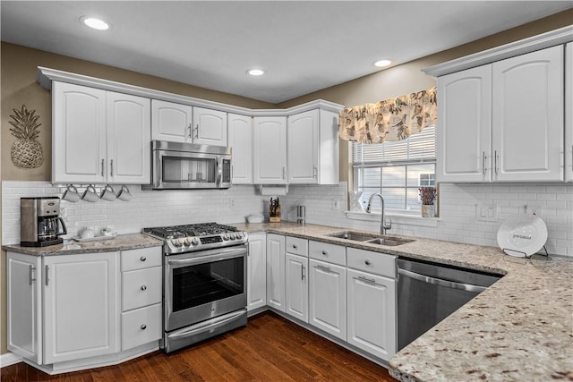 kitchen with white cabinetry, sink, light stone countertops, dark wood-type flooring, and appliances with stainless steel finishes