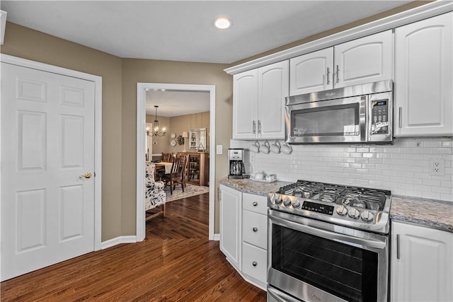 kitchen with white cabinets, stainless steel appliances, light stone counters, and dark hardwood / wood-style floors