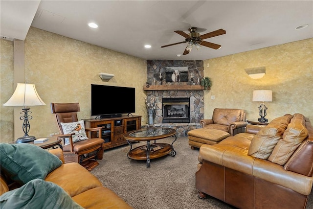 living room featuring ceiling fan, a stone fireplace, and carpet floors