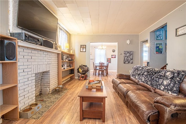 living room with a brick fireplace, an inviting chandelier, and light hardwood / wood-style flooring