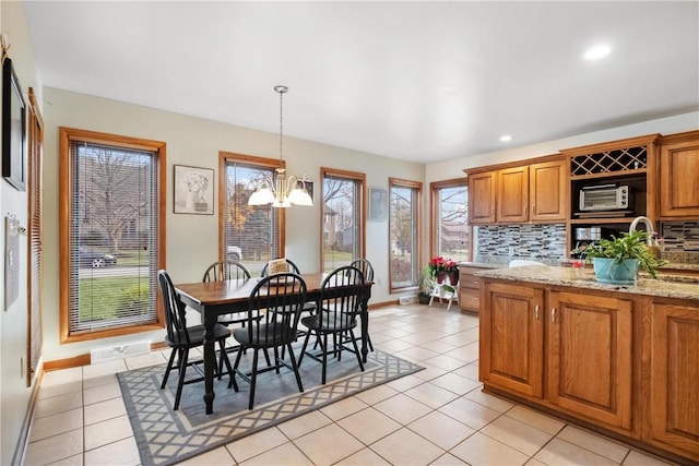 kitchen featuring decorative backsplash, light stone countertops, light tile patterned floors, and a notable chandelier