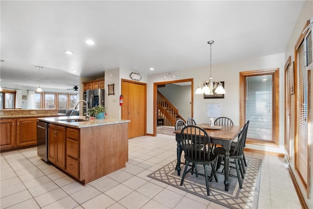 kitchen with ceiling fan with notable chandelier, stainless steel appliances, sink, decorative light fixtures, and an island with sink