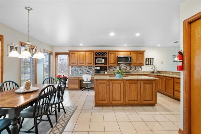 kitchen featuring light stone countertops, sink, tasteful backsplash, kitchen peninsula, and pendant lighting