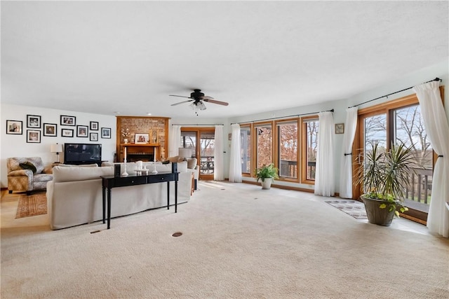 living room featuring ceiling fan, a fireplace, and light carpet