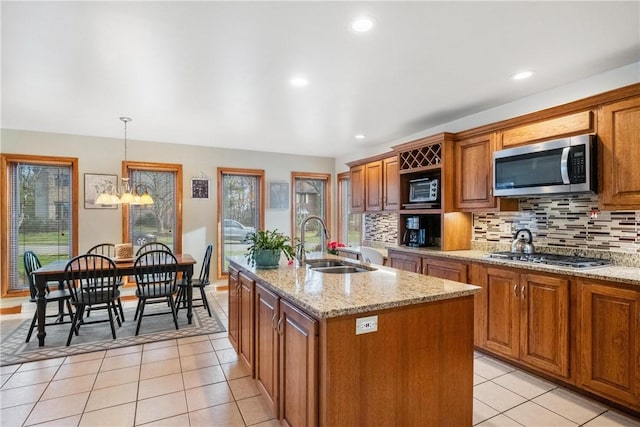 kitchen with appliances with stainless steel finishes, sink, decorative light fixtures, an inviting chandelier, and an island with sink