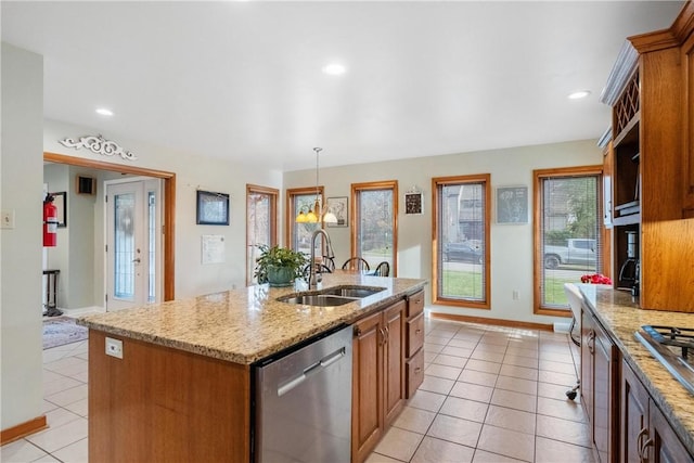 kitchen featuring light stone countertops, appliances with stainless steel finishes, sink, a center island with sink, and hanging light fixtures