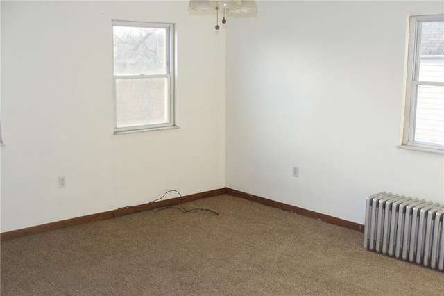 spare room featuring carpet flooring and radiator heating unit