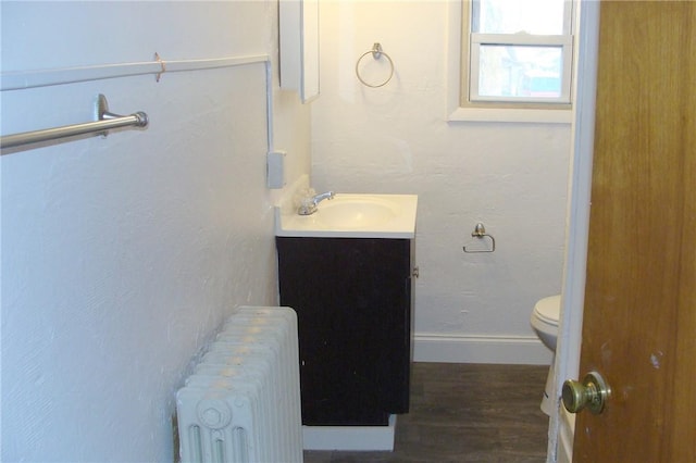 bathroom with radiator, vanity, wood-type flooring, and toilet