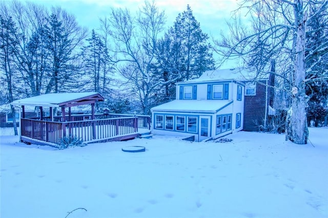 snow covered back of property with a deck