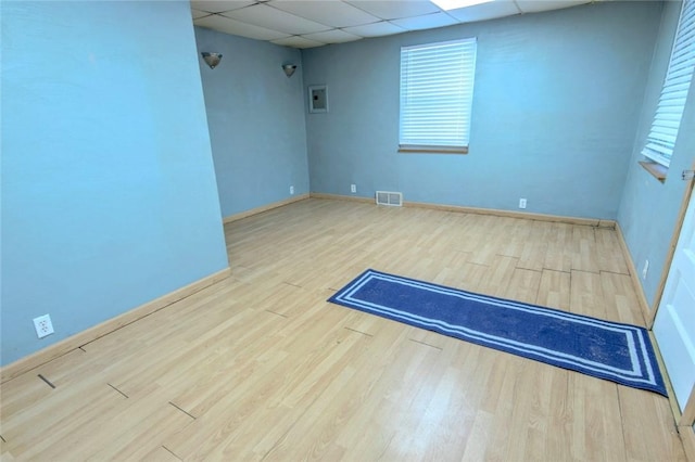 unfurnished room with hardwood / wood-style floors and a drop ceiling