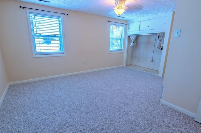 carpeted spare room featuring a healthy amount of sunlight and a textured ceiling