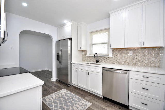 kitchen featuring sink, dark hardwood / wood-style flooring, backsplash, white cabinets, and appliances with stainless steel finishes