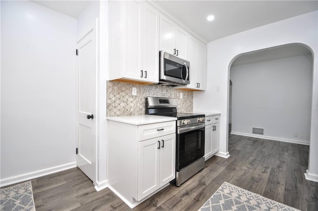 kitchen with appliances with stainless steel finishes, tasteful backsplash, white cabinetry, and dark wood-type flooring