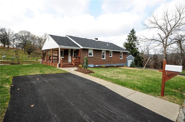 view of front of home with an outbuilding, a front lawn, covered porch, and a garage