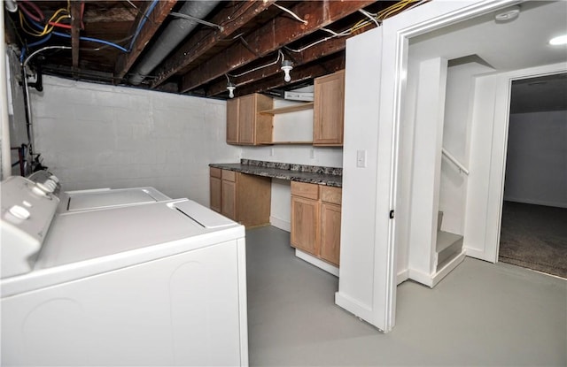 clothes washing area with separate washer and dryer and cabinets