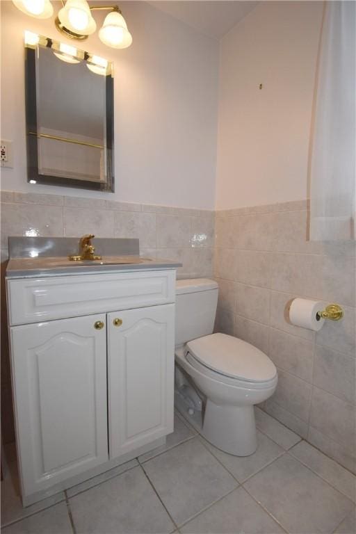 bathroom featuring tile patterned flooring, vanity, tile walls, and toilet