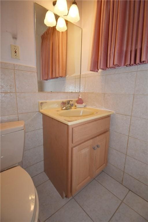 bathroom featuring toilet, vanity, tile patterned floors, and tile walls