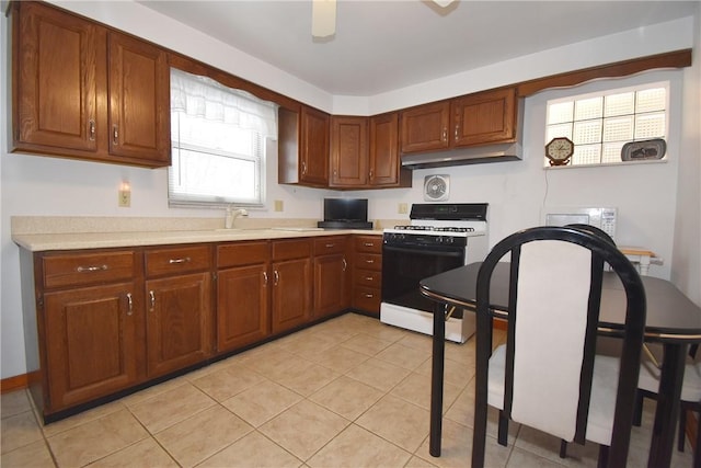 kitchen with sink, light tile patterned floors, and white stove