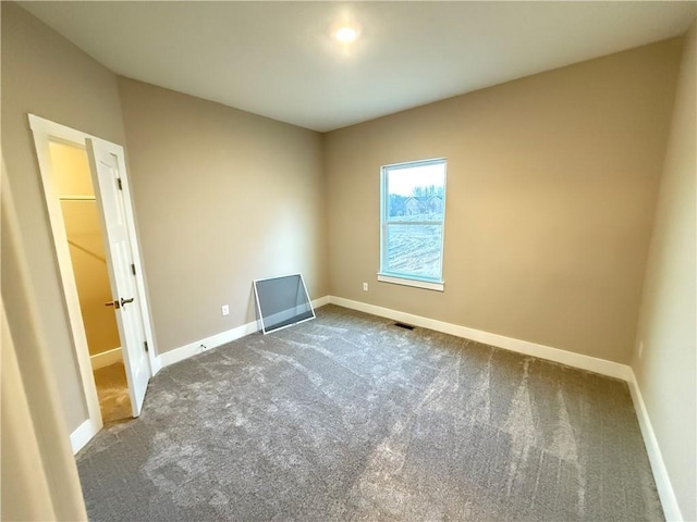 unfurnished bedroom featuring dark colored carpet and baseboards