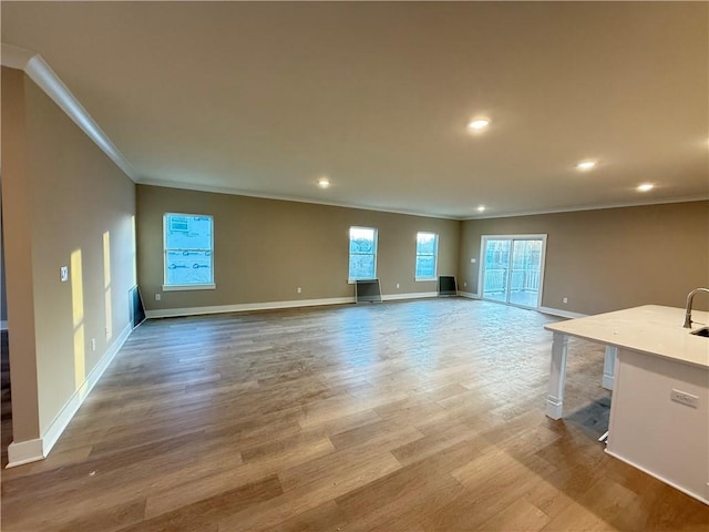 unfurnished living room with crown molding, baseboards, wood finished floors, and recessed lighting